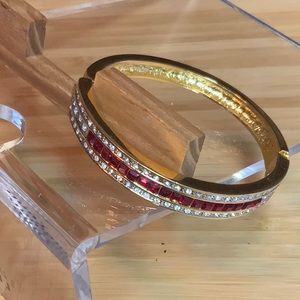 Gold tone oval 7” hinged bangle bracelet with red and clear crystal stones.